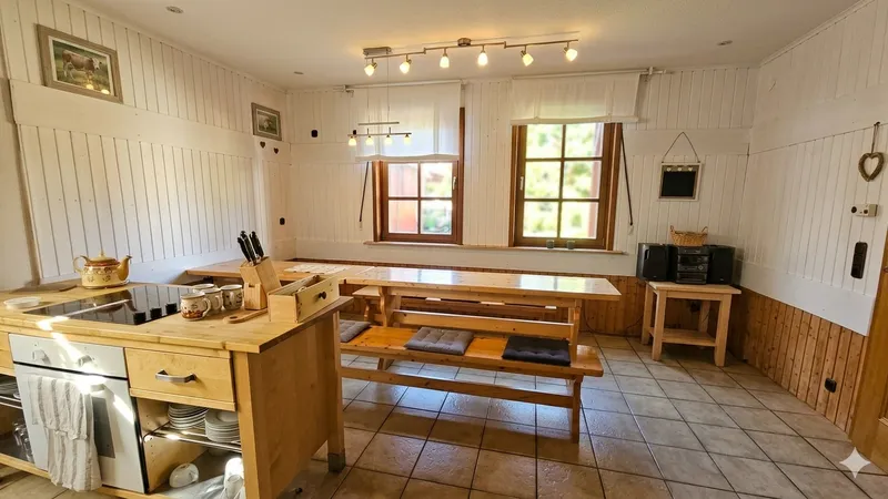 Gemeinschaftsküche mit Herd, Backofen und großem Holztisch