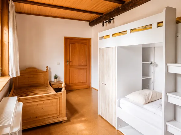 Altenburg – Rustikales Schlafzimmer mit Etagenbett und Einzelbett unter Holzbalkendecke